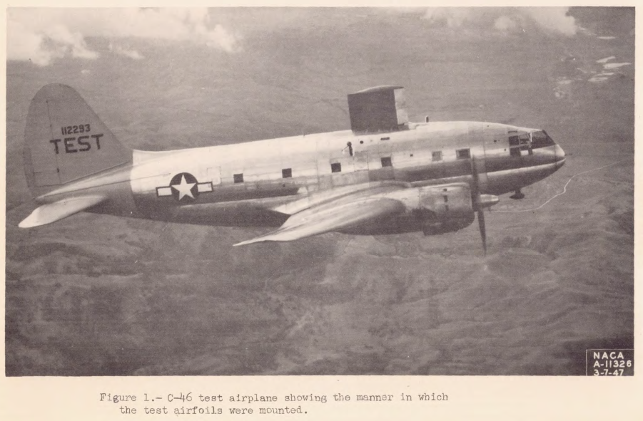 A C-46, a large two engine, propeller driven low-wing airplane. It is modified for icing flight test, with a large (8 ft. by 5 ft.) test airfoil is mounted on top of the body. TEST is emblazened on the tail.